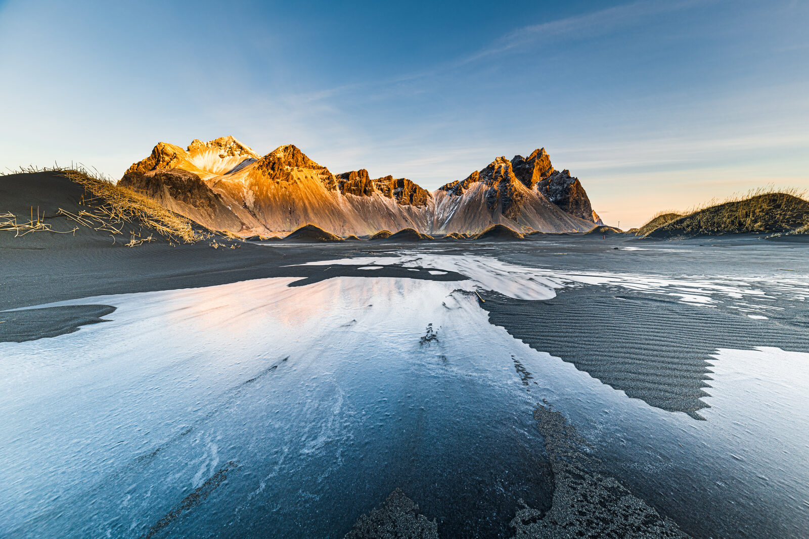 Vestrahorn in low sun above black sand glazed with ice
